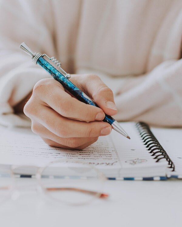A woman's hands writing a note in a notebook